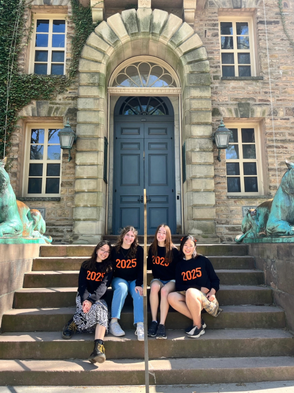 Four Princeton students posing in front of Nassau Hall wearing class sweaters on declaration day.