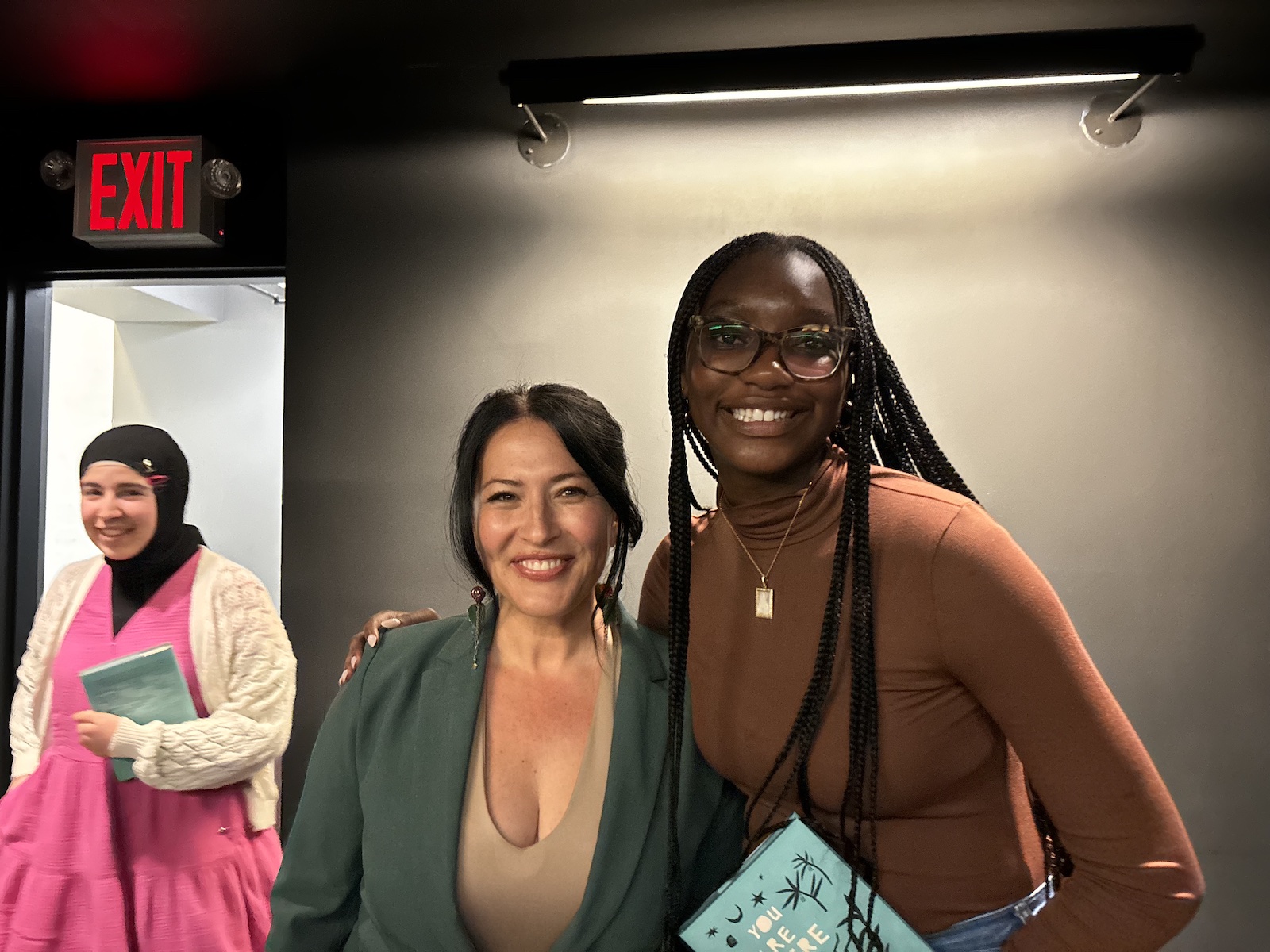 Two women smiling, one holding a turquoise book