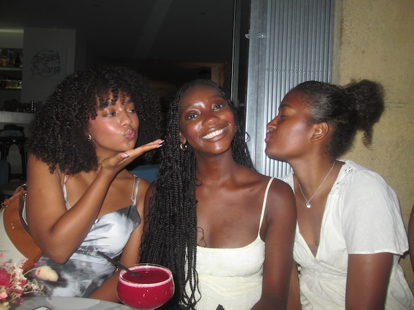 Three girls at a restaurant, two blow kisses, and one smiles.