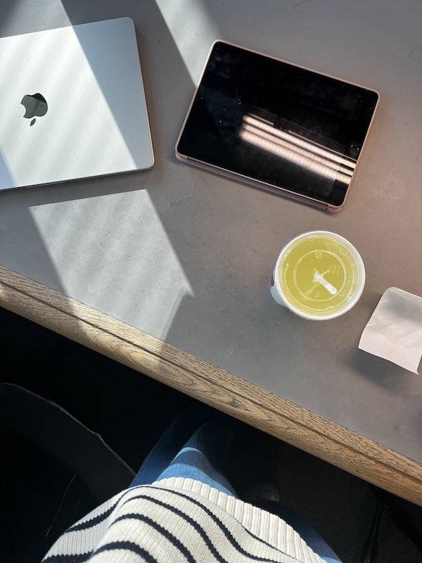 A laptop, iPad, and soda cup on a gray library table