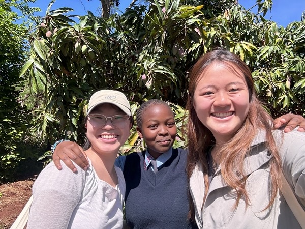 A selfie of myself, our Daraja student tour guide, and another Princeton student in front of a mango tree